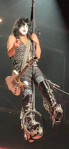 a man with white makeup and black hair on stage holding a guitar