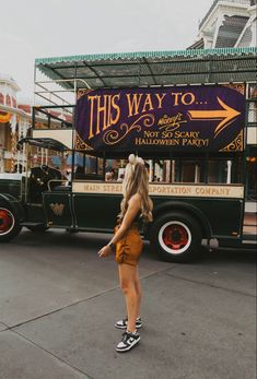 a woman standing in front of a food truck that says this way to halloween party