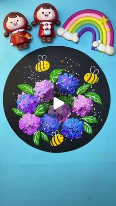 some little figurines sitting on top of a black plate with flowers and bees