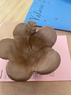 a clay sculpture sitting on top of a piece of paper