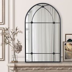 a mirror sitting on top of a mantle next to a vase with flowers