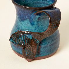 a blue and brown vase sitting on top of a white table