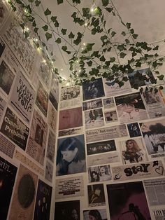 a wall covered in posters and lights with ivy hanging from it's ceiling above