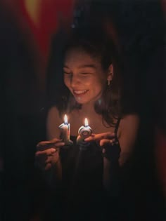 a woman holding two lit candles in her hands