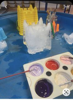 an ice tray with paint and brushes on it, next to some plastic castle molds