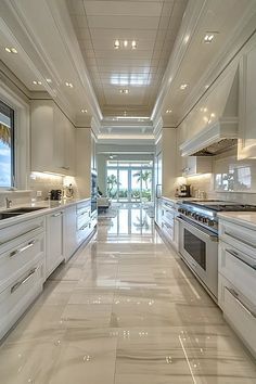 a long kitchen with white cabinets and marble flooring is pictured in this image from the front view