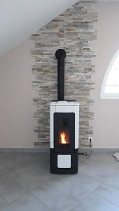 a fireplace in the corner of a room with a stone wall and window above it