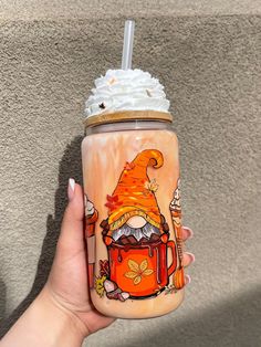 a hand holding a cup with whipped cream and an orange frosted drink in it