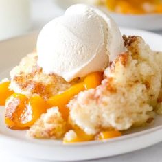 a white plate topped with a scoop of ice cream on top of fruit cobbler