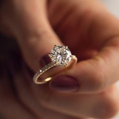 a close up of a person holding a ring with a diamond in it's hand