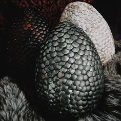 two black and white eggs sitting on top of a fur covered bedding with dark background