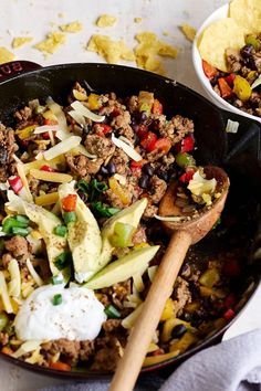 a skillet filled with taco salad and tortilla chips on the side