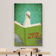 a white bird sitting on top of a green book next to two wooden desks