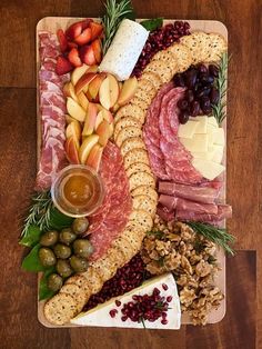 an assortment of meats, cheese and fruit on a platter with crackers