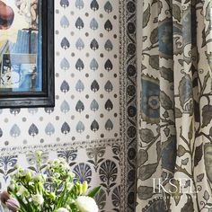 a vase filled with flowers sitting in front of a wallpapered wall next to a mirror