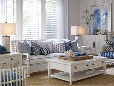 a living room with white furniture and blue accents