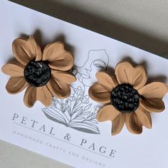 two brown flowers with black centers are sitting on a card