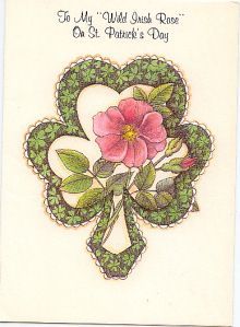 a card with a pink flower on it's center and green leaves in the shape of a heart