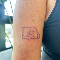 a woman's arm with a small tattoo of a dog sitting in a car