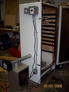 a white refrigerator sitting inside of a room next to a wall with wires hanging from it's sides