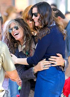 two women hugging each other in front of a group of people with sunglasses on their faces