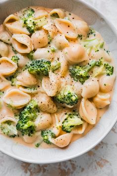 a bowl filled with pasta and broccoli on top of a white tablecloth