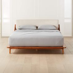 a bed sitting on top of a hard wood floor next to a white wall in a bedroom