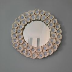 a round mirror is mounted on the wall with blue and white circles around it's edge