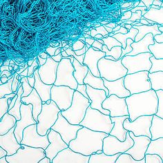 blue fishing nets are laying on the white surface, with one knoted up to the net