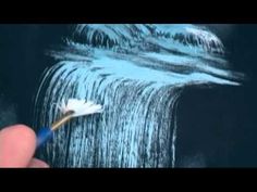 a hand holding a toothbrush in front of a waterfall with water coming out of it