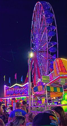 an amusement park at night with ferris wheel and carnival rides in the background, lit up by colorful lights