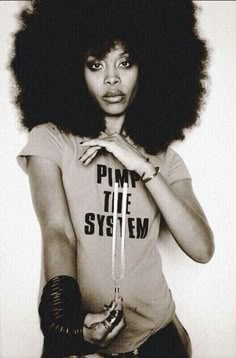 a woman with an afro is holding her hand on her hip and looking at the camera