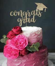 a cake with pink frosting and flowers on top that says congrats grad