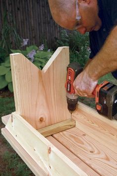 a man is using a drill to attach the top of a wooden bench with two power tools