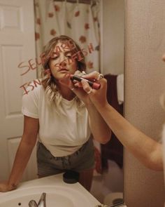 a woman brushes her teeth in front of a mirror with words written on the mirror