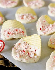 cookies with white frosting and red sprinkles are on a baking sheet