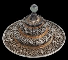 an intricately designed silver plate with a glass ball on it's center piece