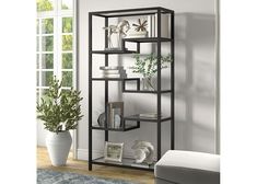 a black shelf with books and plants on it in a living room next to a window