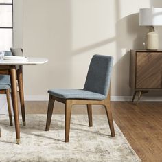 a dining room table with two chairs next to it and a rug on the floor