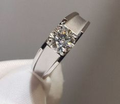 a diamond ring sitting on top of a white cloth covered napkin with a silver band