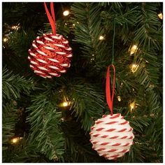 christmas ornaments hanging from a tree with red and white striped decorations on it's branches