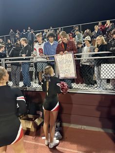 two cheerleaders holding up a sign at a football game