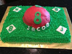 a birthday cake with green grass and red ball on it