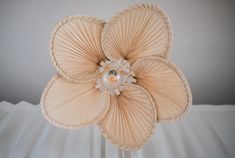 a flower made out of paper sitting on top of a bed