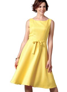 a woman wearing a yellow dress with a bow at the waist and sleeves, standing in front of a white background