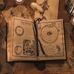 an open book sitting on top of a wooden table next to candles and other items