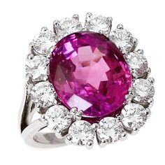 A beautiful and vibrant 10+ carat oval pink sapphire accented with a cluster of twelve round brilliant cut diamonds weighing approximately three carats, with (H/I color, VS-SI clarity), set in 18kt white gold. The pink sapphire displays exceptional clarity, measures excellent proportions of 13 x 11 x 7 mm, and accompanies a gemological report from AGL stating the origin as Ceylon (Sri Lanka) with indications of low temperature heating and no clarity enhancement. Pink Sapphire Rings, Pink Sapphire Jewelry, Vintage Cluster Ring, Jewerly Ring, Pink Diamonds, Cluster Rings, Pink Bling, Expensive Jewelry, Pink Jewelry