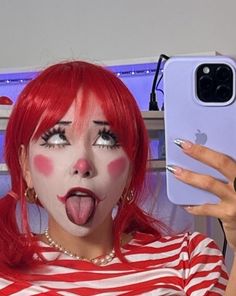 a woman with red hair and makeup making a funny face while holding up her cell phone