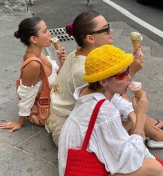 three women sitting on the ground eating ice cream