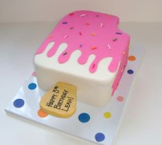 a birthday cake with pink frosting and sprinkles on it's side